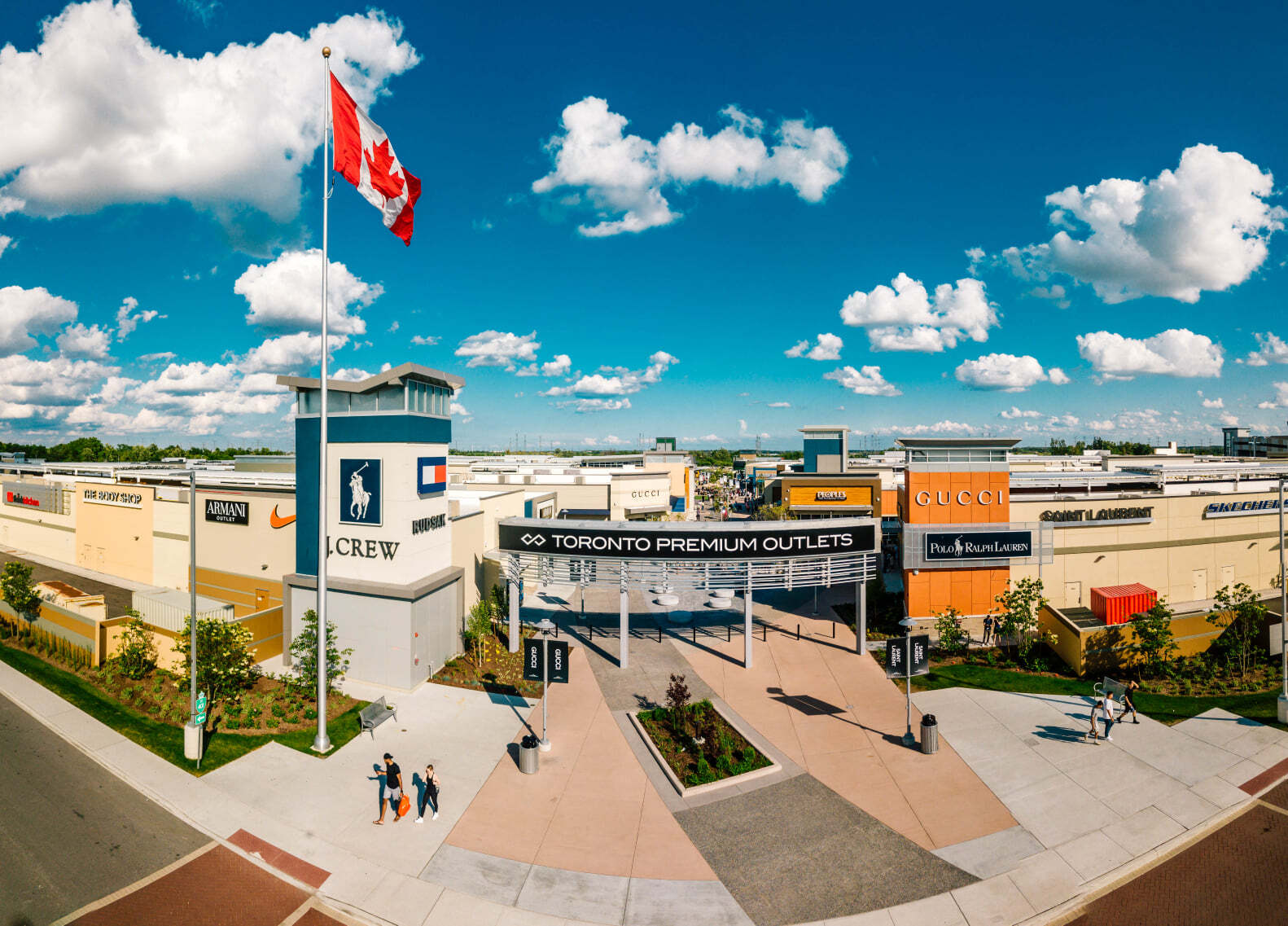 Aerial view of the Toronto premium Outlets building. It is a sunny day. The Canadian flag waves at the entrance.