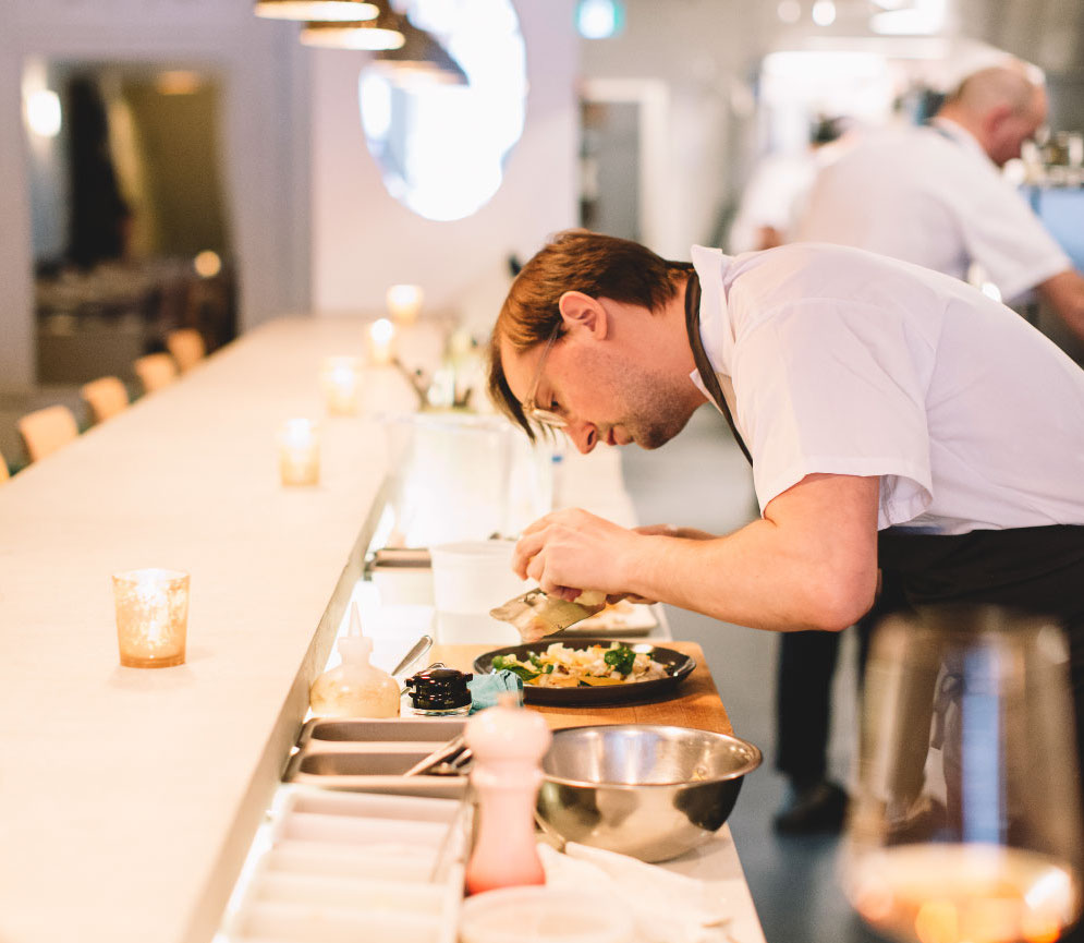 chef leaning to garnish a dish in the kitchen of Grey Gardens